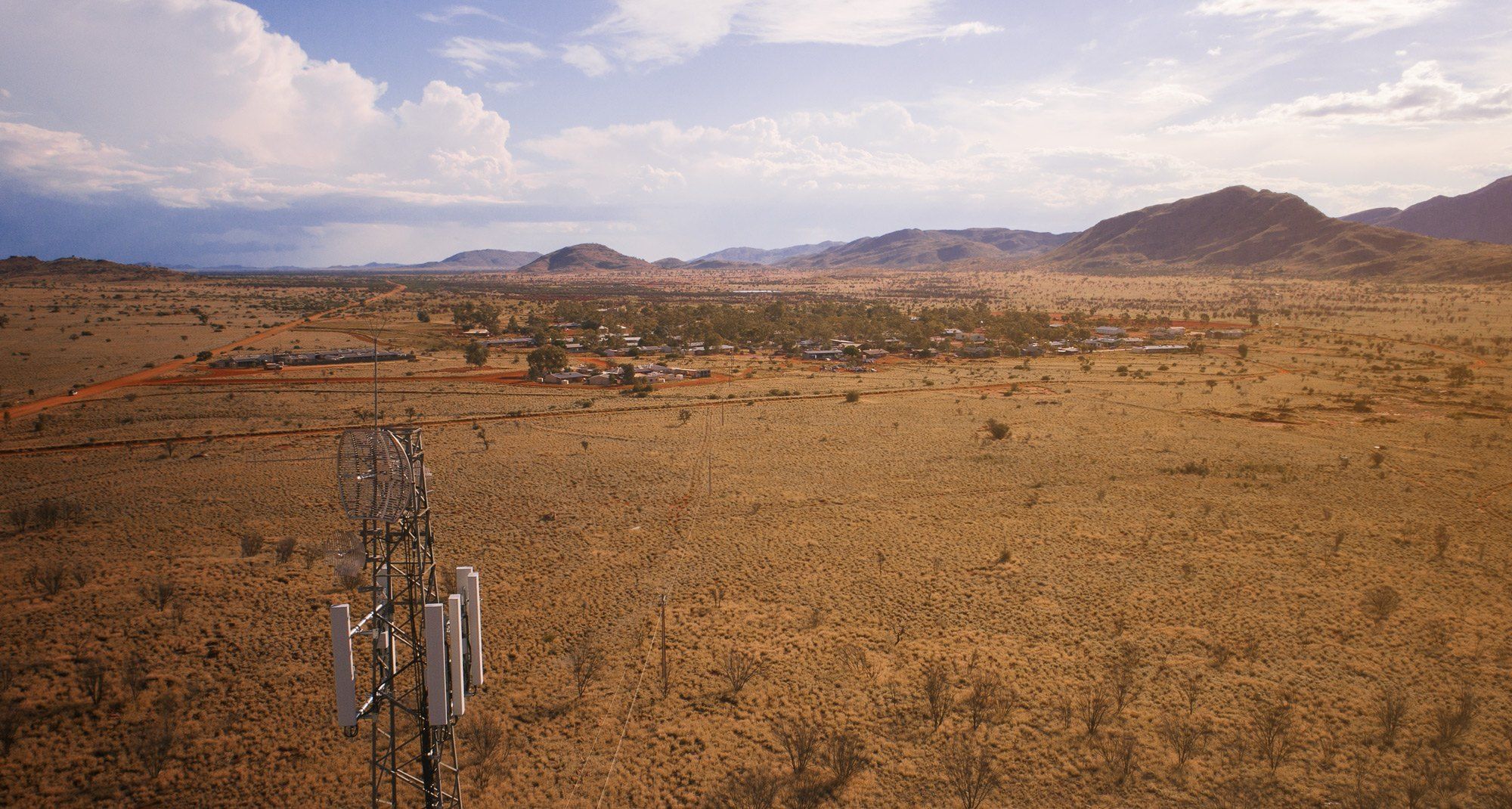 Red earth and low scrub stretching to the ranges near Amata, under a pale sky