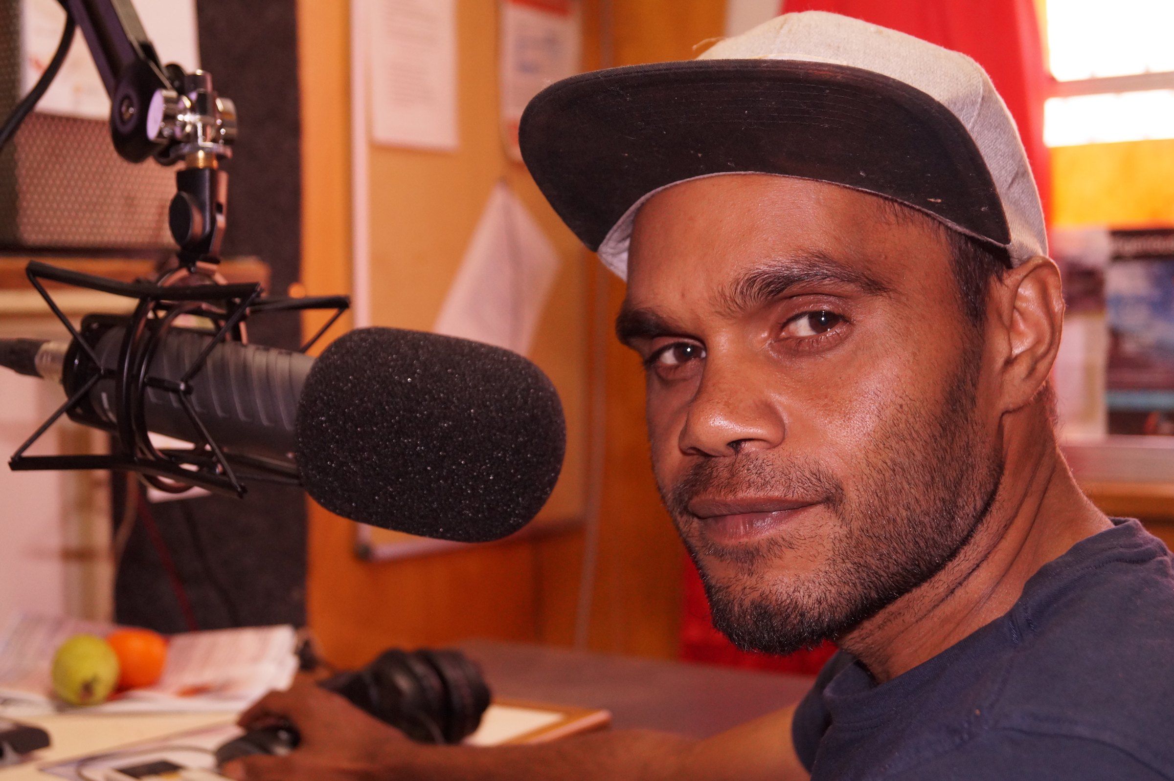 A broadcaster speaking into a microphone at an outside broadcast in Mimili