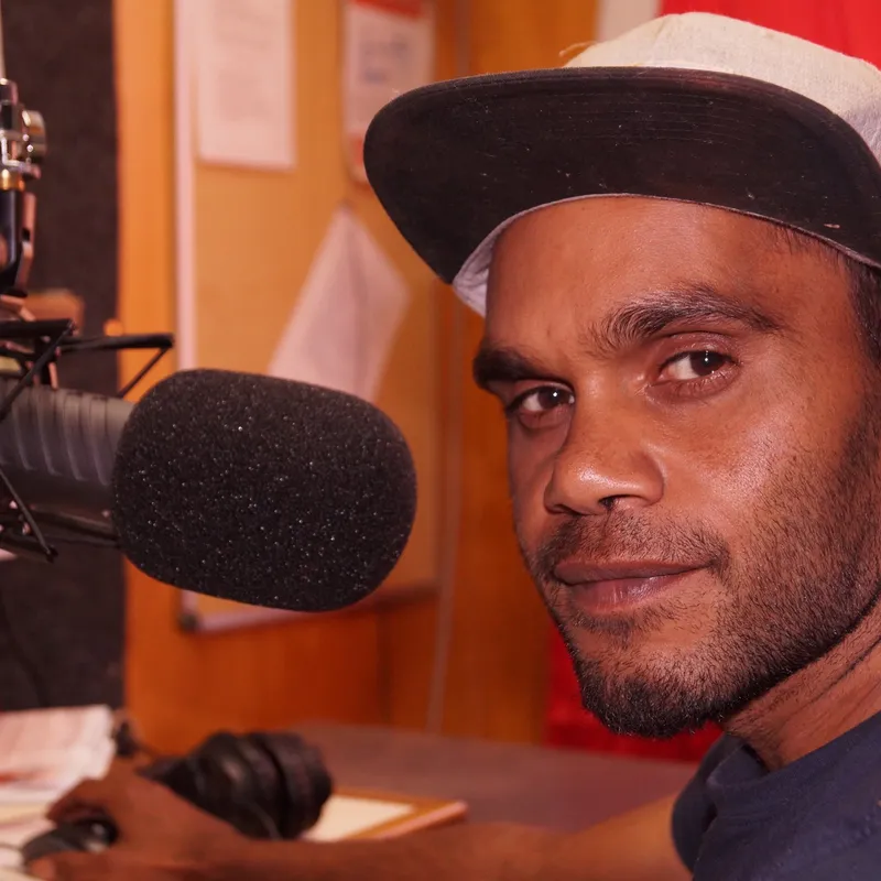 Broadcaster at the microphone during an outside broadcast in Mimili