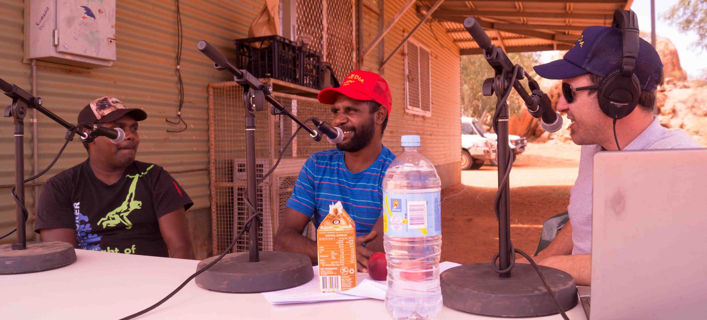 Outside broadcast table with microphones set up on red earth