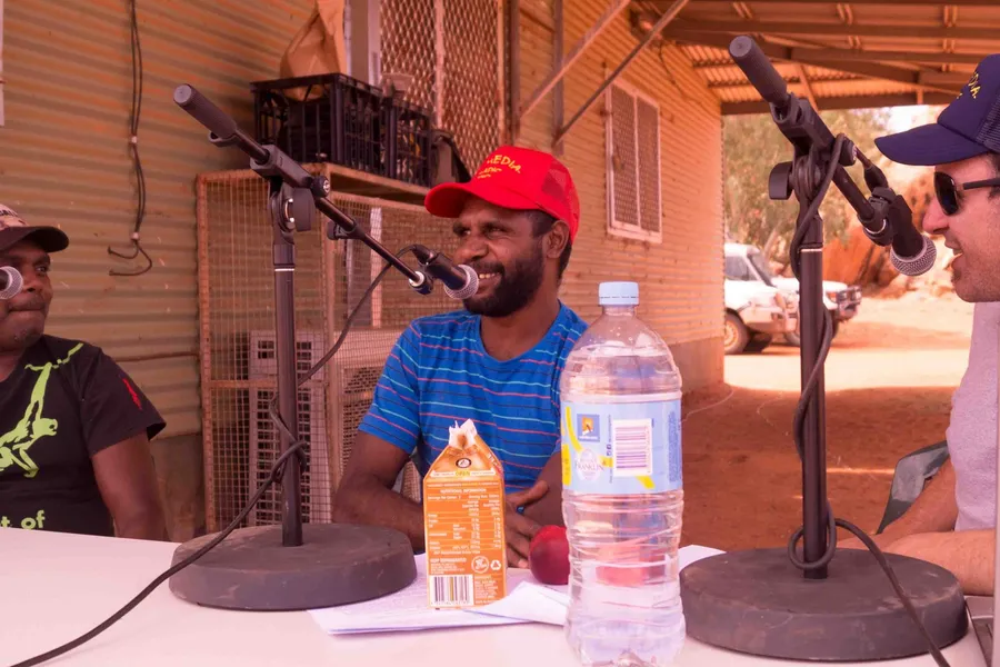 Outside broadcast table with microphones set up on red earth